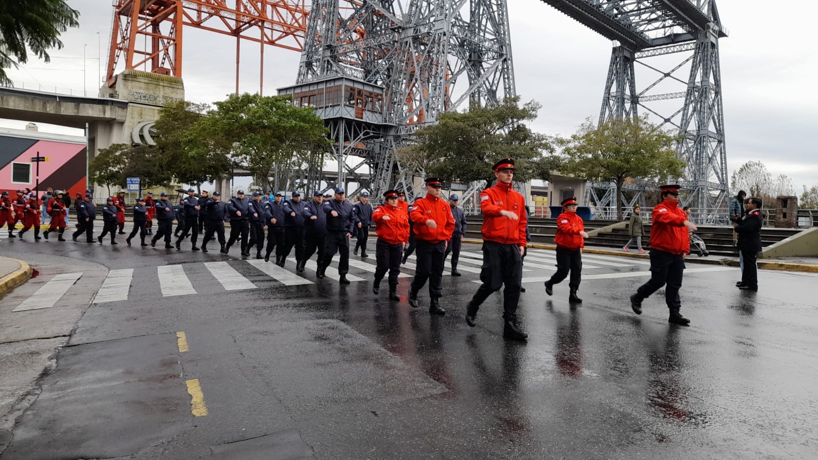 Formación de bomberos de Vuelta de Rocha marchando en columna bajo el puente Nicolás Avellaneda, en el barrio de La Boca